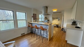 Et moderne køkken med en central ø, barstole og store vinduer.