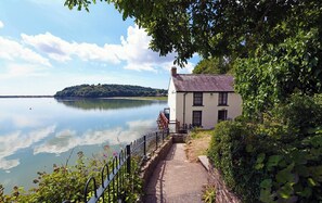 A lakeside property with a white building, a pathway, and a view of the lake. - 2 Rock Cottage, Llansteffan (Llansteffan)