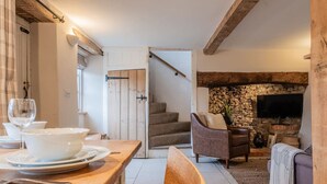 A cozy living room with a stone fireplace, a comfortable sofa, and a television. - The Gamekeeper`s Cottage - Stunning 2 Bed (Leafield)