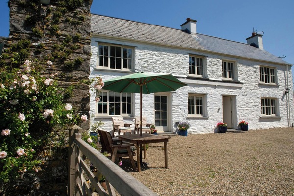 Front of the cottage with garden, chairs and parasol