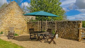 A stone building with a gravel patio, outdoor seating, and a wooden gate.
