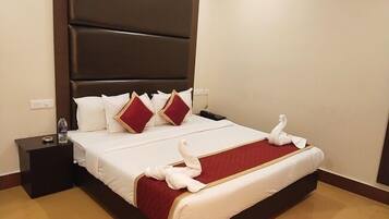 Een hotelkamer met een groot bed, een donker hoofdeinde, witte en rode kussens, een rode spreideken en een zwanendecoratie.