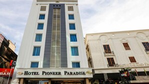 Un hotel llamado "Hotel Pioneer Paradise" con una fachada moderna y varias ventanas.