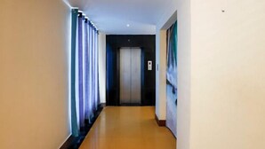 Un pasillo con piso de madera, una puerta al final y un cuadro en la pared.