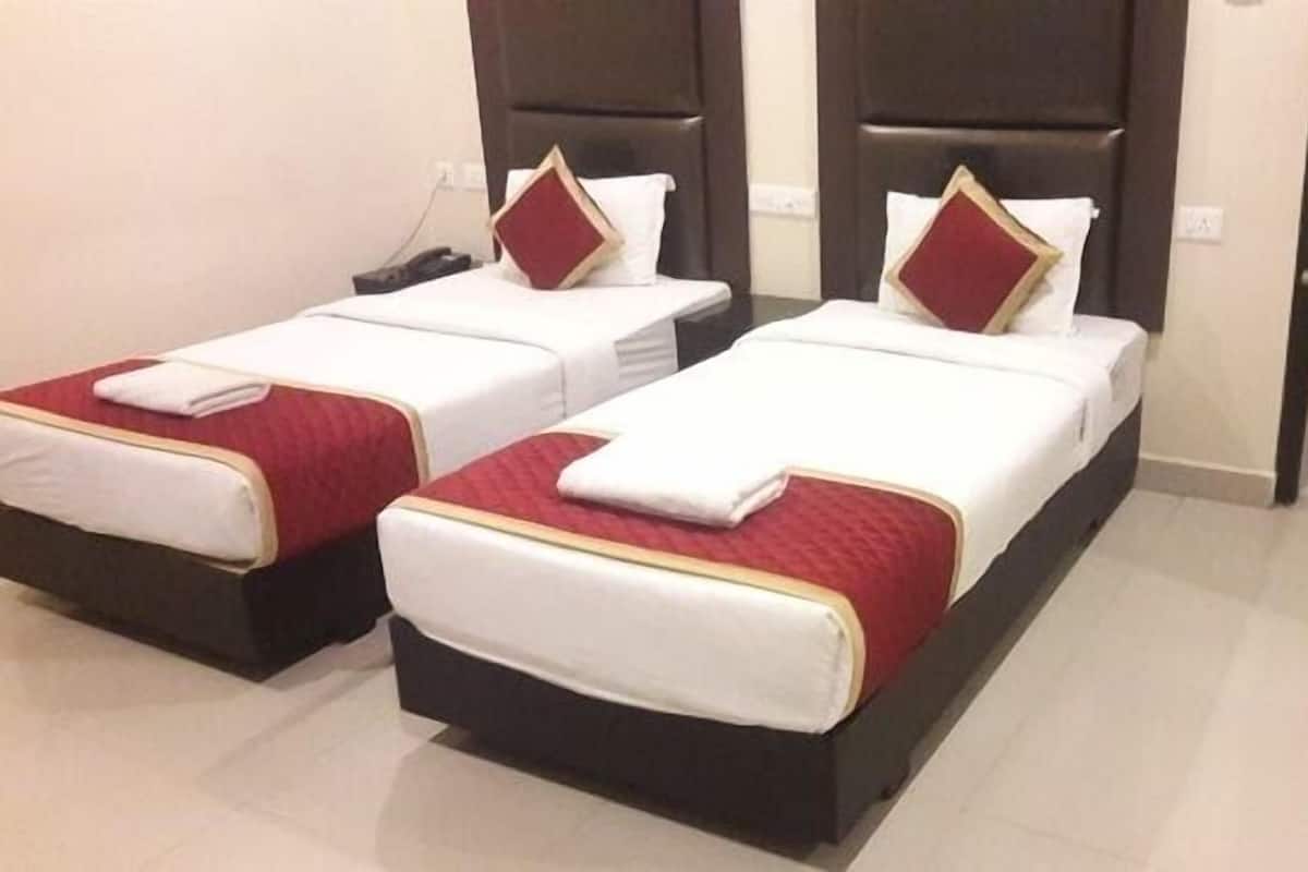 Two single beds with red and white bedding, a dark headboard, and a white wall.