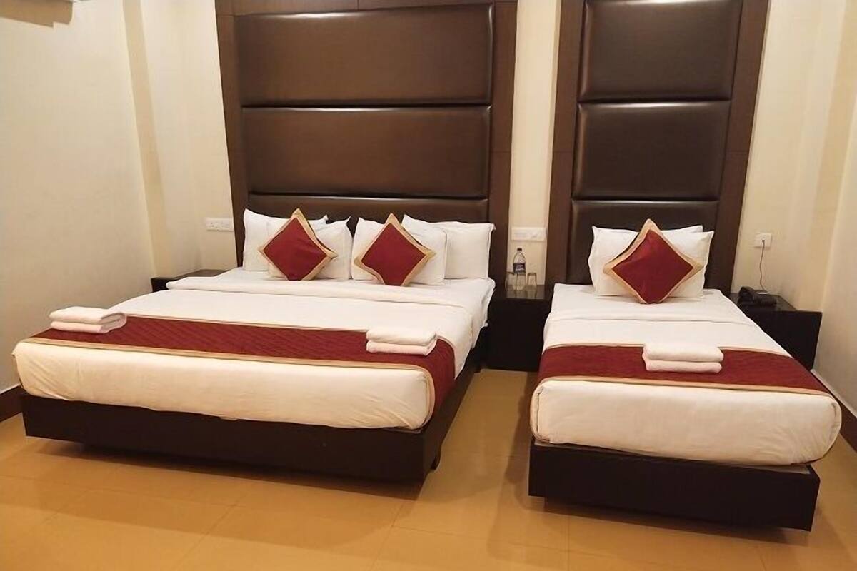 Two twin beds with dark headboards, white bedding, and red accents.