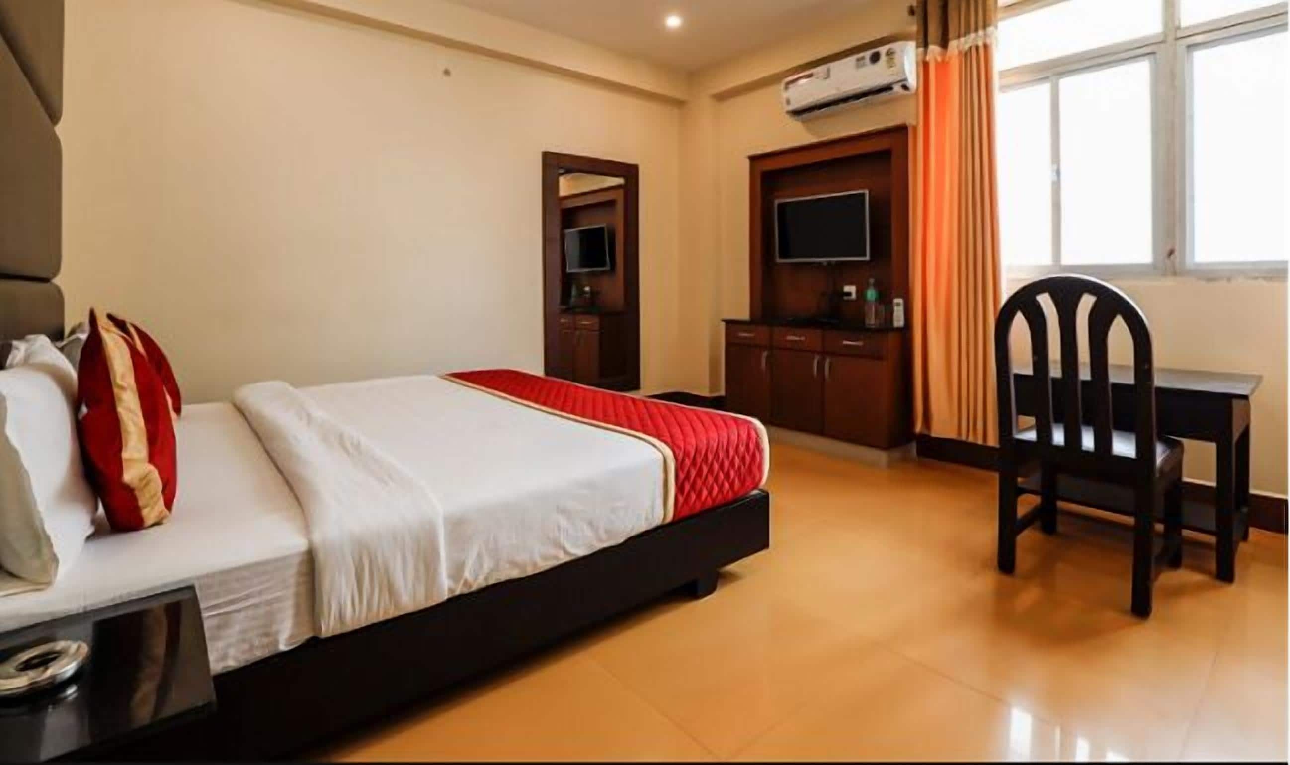 Une chambre d’hôtel avec un lit, un bureau, une chaise et un téléviseur.