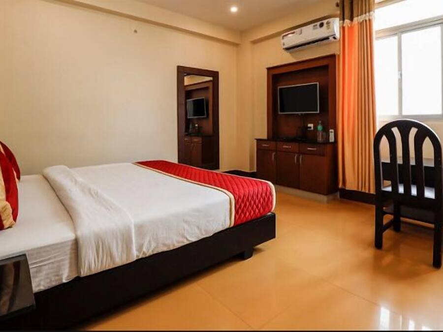 A hotel room with a bed, a desk, a chair, and a television.