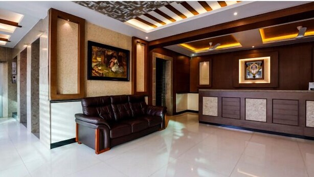 Un vestíbulo moderno con un sofá de cuero, una mesa de recepción e iluminación empotrada en un techo con diseño decorativo.