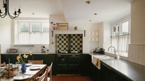 Una cucina con zoccolo a scacchi, un fornello e un'area pranzo con un tavolo apparecchiato per due.