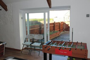 Ein Zimmer mit einer Fußballstoßmaschine, zwei Stühlen und einer Glastür zu einem Hinterhof mit Holzzaun.