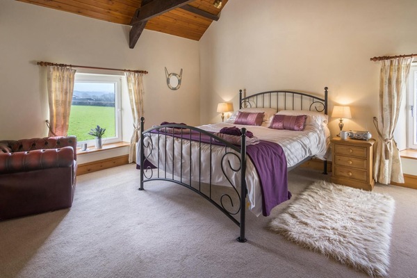 King size bed with bedside cabinets and lamps, armchair and rug on the floor