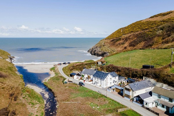 Drone view of Cwm Tydu, village houses on road to beach, stream and sea
