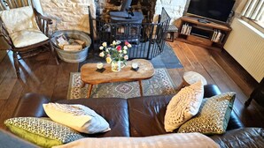 Un salon chaleureux avec une cheminée en pierre, un canapé en cuir et un téléviseur.