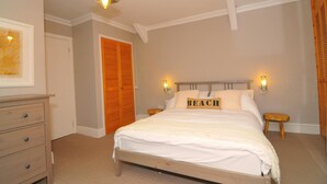 A bedroom with a wooden bed, two bedside tables, a nightstand, a wooden wardrobe, and a ceiling light fixture. - 2 Castle Hall, Llangrannog (Llangrannog)