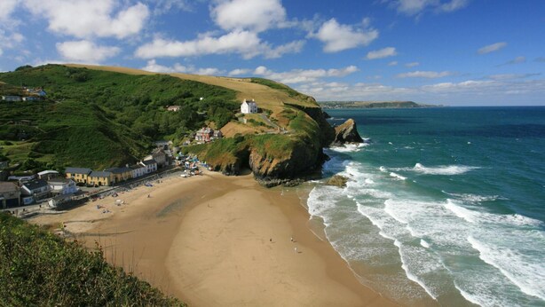 A coastal town with a sandy beach, a prominent white building on a cliff, and a view of the sea. - 2 Castle Hall, Llangrannog (Llangrannog)