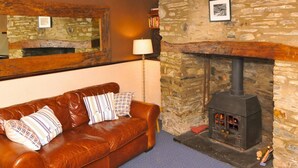 A cozy room with a stone fireplace, a leather sofa, and a mirror on the wall. - 2 Castle Hall, Llangrannog (Llangrannog)
