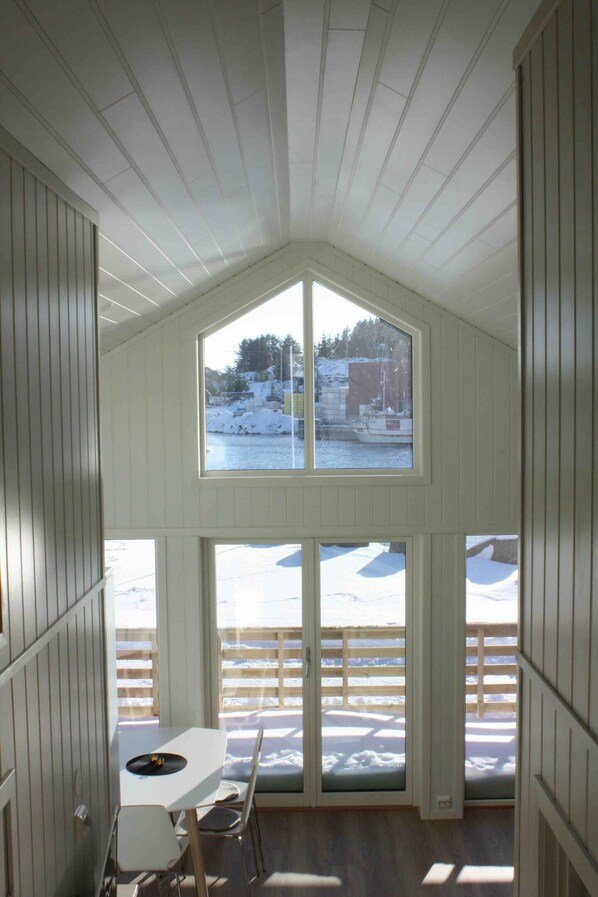A room with a high ceiling, a large window, and a view of a snowy outdoor area. - Hjellebua - Stamsund, in the heart of Lofoten (Stamsund)