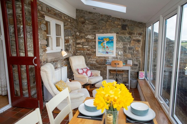 Conservatory with dining table and chairs, armchairs and garden views