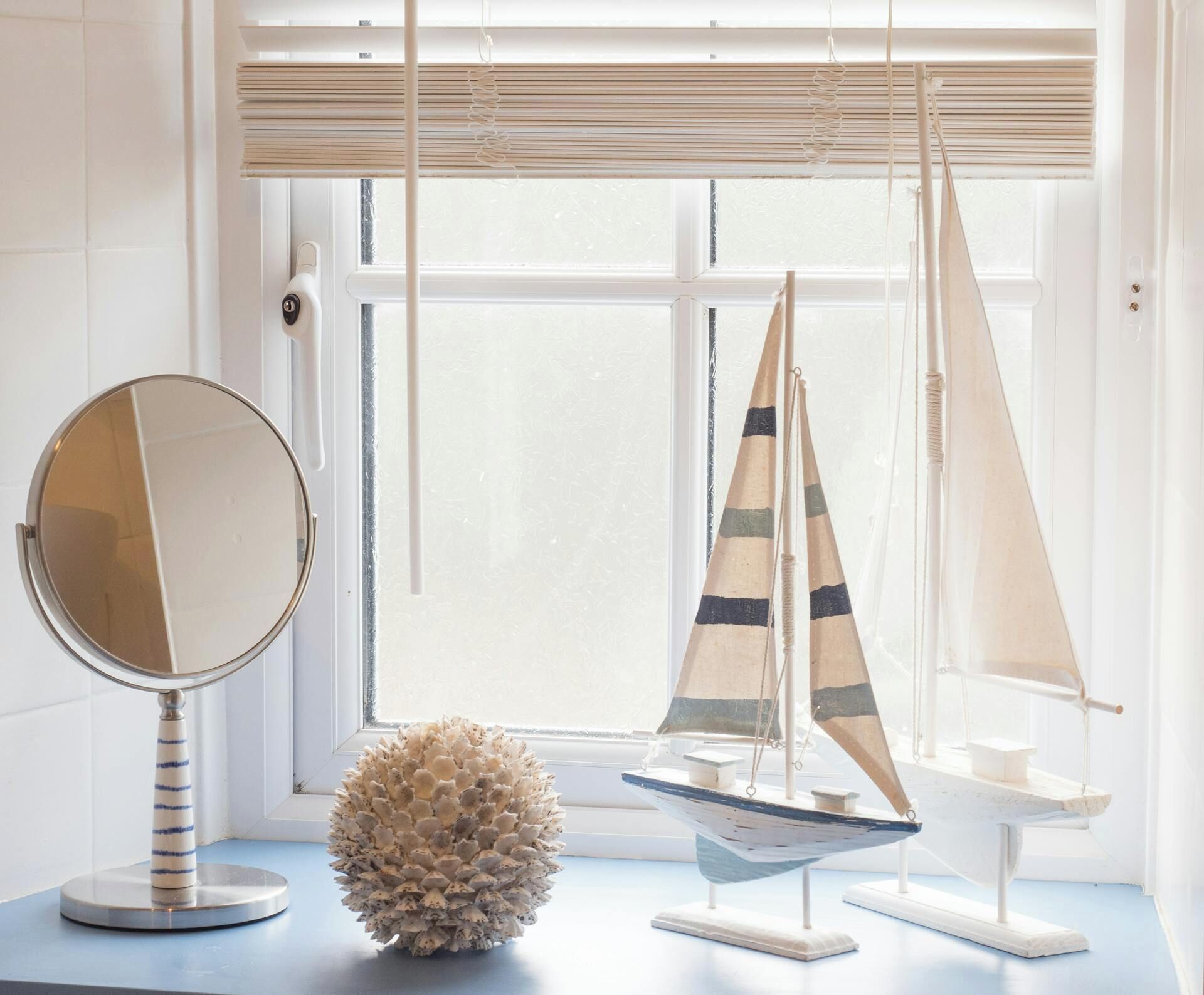 Une pièce avec un miroir rond, un modèle de voilier et un objet décoratif posé sur une surface bleue.