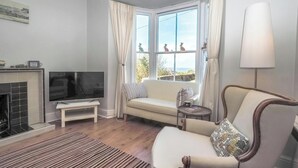 A living room with a television, sofa, armchair, and a fireplace. - Brodawel, New Quay - Three Bedroom Cottage, Sleeps 6 (New Quay)
