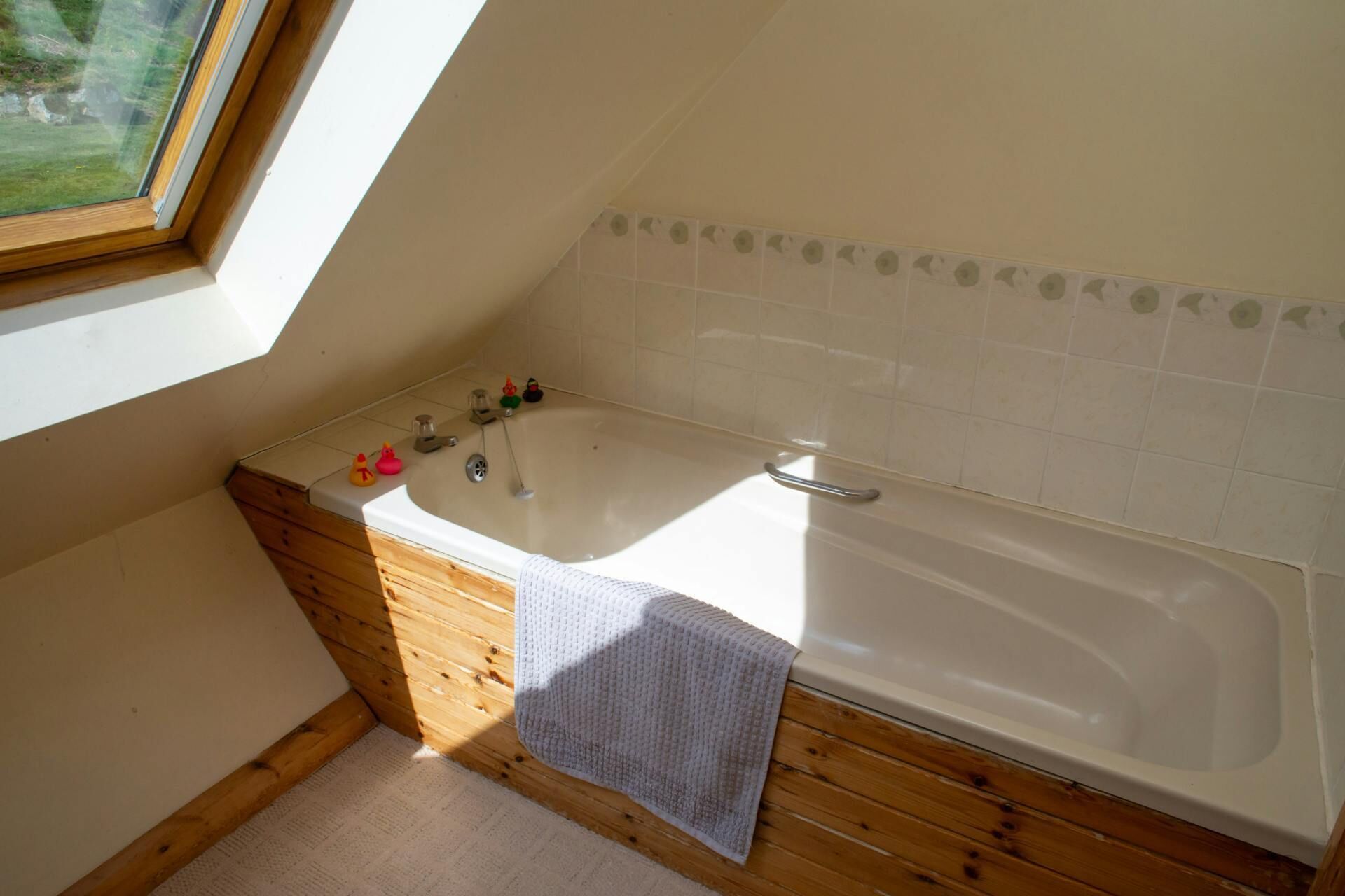 Une salle de bain moderne avec une baignoire sur pieds, un lambris en bois, une petite fenêtre et une zone de douche carrelée.