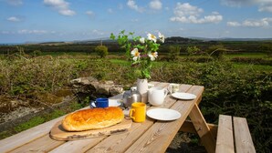 Ein Picknick mit Brot, Blumen in einer Vase und einem Tisch mit Tassen und einem Wasserkocher.