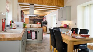 Una cocina moderna con vigas de madera, una isla central y un comedor con sillas y una mesa.