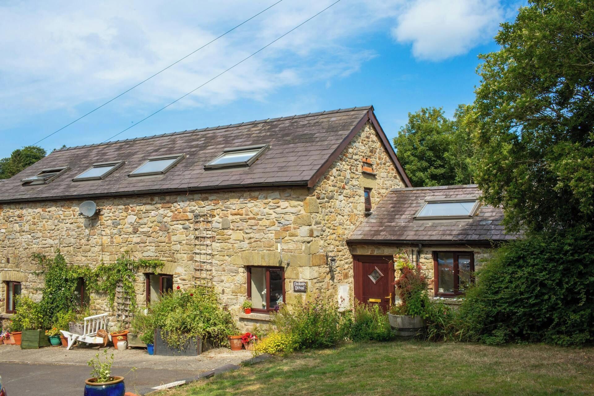 A stone building with a sloped roof, multiple windows, and a sign indicating a business.