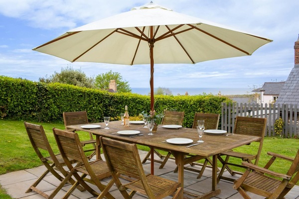 Wooden garden table with chairs on the lawn and laid with drinks