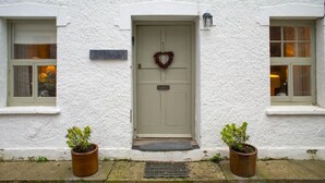 Un bâtiment blanc avec une porte, deux fenêtres et une guirlande sur la porte.