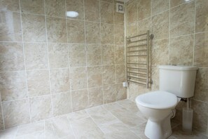 A bathroom with beige tiles, a white toilet, and a towel rack. - Ellesmere, New Quay - Three Bedroom Cottage, Sleeps 5 (New Quay)
