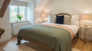 Une chambre avec un plafond en pente, un lit avec une tête de lit, deux lampes de chevet, une fenêtre avec vue et un radiateur.