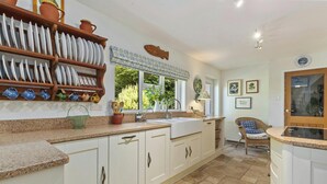 A kitchen with white cabinets, a granite countertop, a sink, and a window with a view of greenery. - Castle Reach, Newport (Newport)