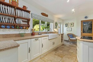 A kitchen with white cabinets, a granite countertop, a sink, and a window with a view of greenery. - Castle Reach, Newport (Newport)