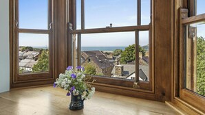 A room with large wooden-framed windows, a wooden floor, and a vase with flowers on a windowsill. - Castle Reach, Newport (Newport)