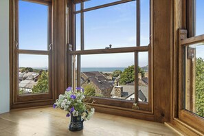 A room with large wooden-framed windows, a wooden floor, and a vase with flowers on a windowsill. - Castle Reach, Newport (Newport)