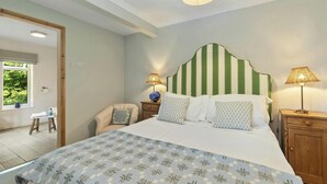 A bedroom with a bed, two bedside tables, a chair, a window with a view, and a door. - Castle Reach, Newport (Newport)