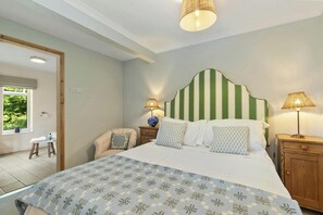 A bedroom with a bed, two bedside tables, a chair, a window with a view, and a door. - Castle Reach, Newport (Newport)