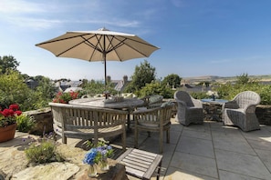 An outdoor patio with wicker furniture, a stone table, and a large umbrella. - Castle Reach, Newport (Newport)