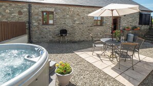 A stone building with a hot tub, outdoor seating, and a barbecue grill. - Eirlys, Aberystwyth - Two Bedroom Cottage, Sleeps 4 (Llanrhystud)
