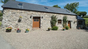 Un bâtiment en pierre avec une allée gravillonnée, une porte en bois et une petite fenêtre.
