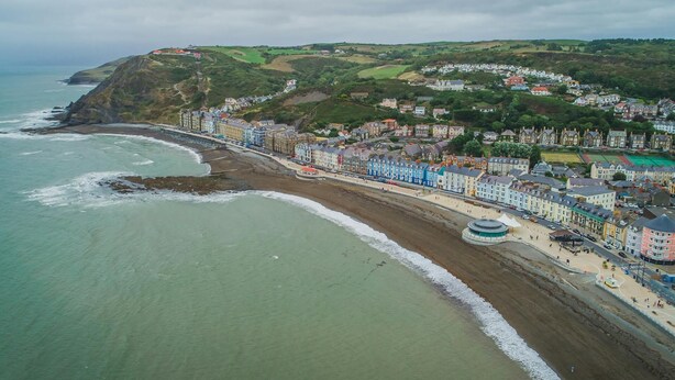 Une ville côtière dotée d’une plage, de bâtiments aux couleurs vives et d’un phare.