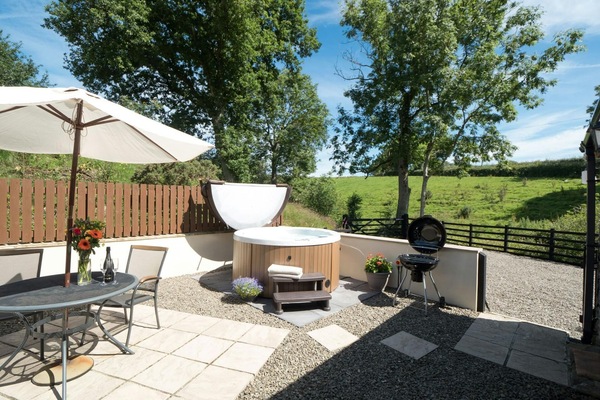 Patio with table, chairs, parasol and hot tub