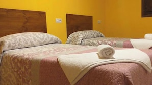 A room with three beds, each with patterned bedding and a rolled towel on the bed. - Los Torrejones caude  (Teruel)