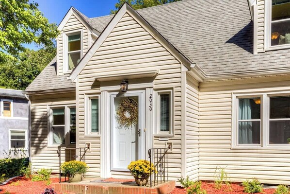 A two-story house with a front porch, a wreath on the door, and a number '2030' above the door.