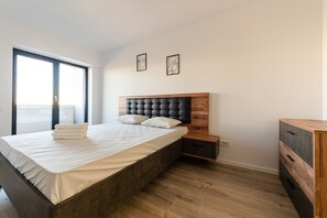 Une chambre à coucher moderne avec un grand lit, une tête de lit en bois et une table de chevet.
