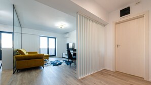 Un salon moderne comprenant un canapé, un téléviseur et un coin repas avec des chaises.