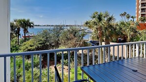 Un balcon avec vue sur la mer et les bateaux, entouré de verdure et de palmiers.