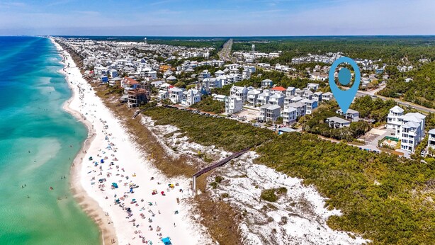 Vista aérea de un pueblo costero con playa, edificios residenciales y un faro.